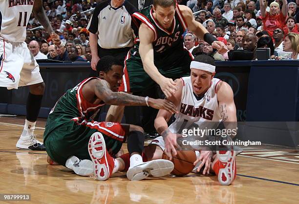 Mike Bibby of the Atlanta Hawks protects a loose ball against Brandon Jennings and Luke Ridnour of the Milwaukee Bucks in Game Seven of the Eastern...