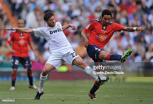 Xabi Alonso of Real Madrid steals the ball from Javad Nekounam of CA Osasuna during the La Liga match between Real Madrid and CA Osasuna at Estadio...