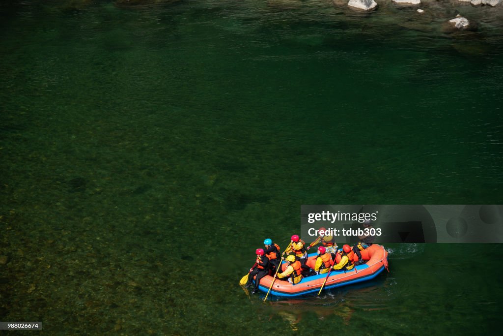 Vista aérea de un grupo de hombres y mujeres rafting en un río tranquilo