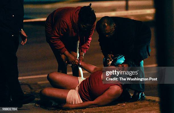 Scene of a multiple shooting with fatalities on South Capitol Street in Southeast on March 30, 2010. A grieving woman is comforted at the scene by a...