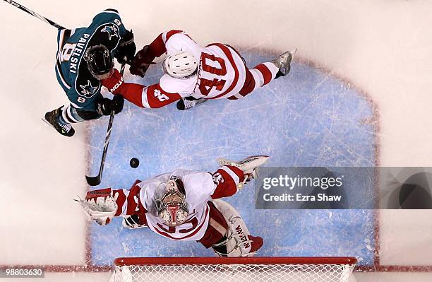 Jimmy Howard of the Detroit Red Wings makes a save while teammate Henrik Zetterberg fights for position with Joe Pavelski of the San Jose Sharks in...