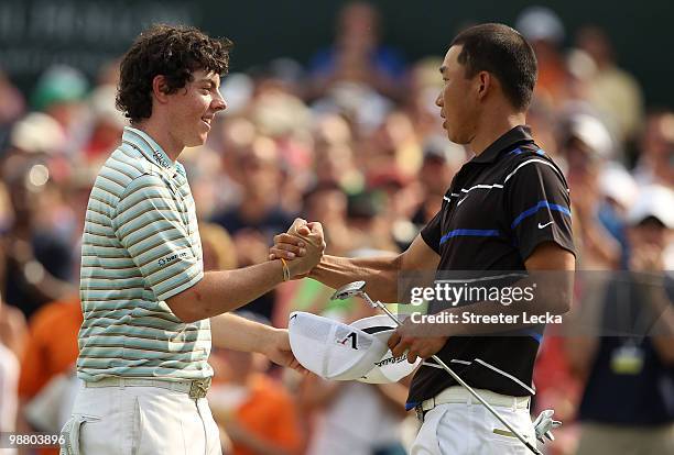 Rory McIlroy of Northern Ireland shakes hands with Anthony Kim on the 18th hole after finishing the final round of the Quail Hollow Championship at...