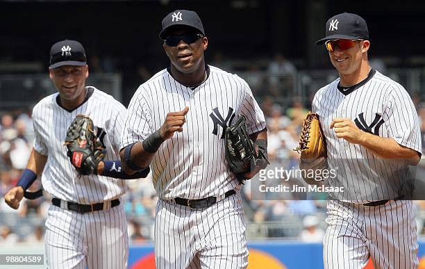 Derek Jeter, Marcus Thames, and Brett Gardner of the New York Yankees run into the dugout after the final out of the second inning against the...
