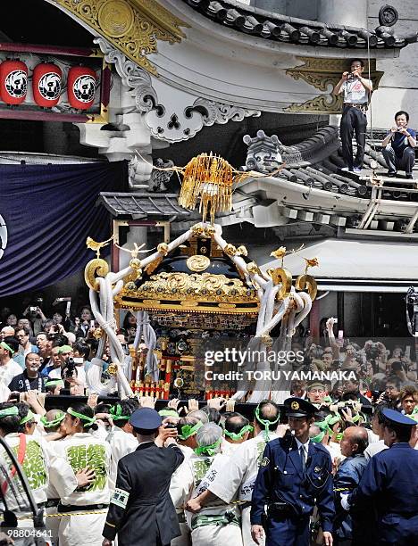 Men carry a portable shrine in front of Kabukiza theatre, home of Japan's traditional kabuki drama that closed its doors last Friday to be demolished...