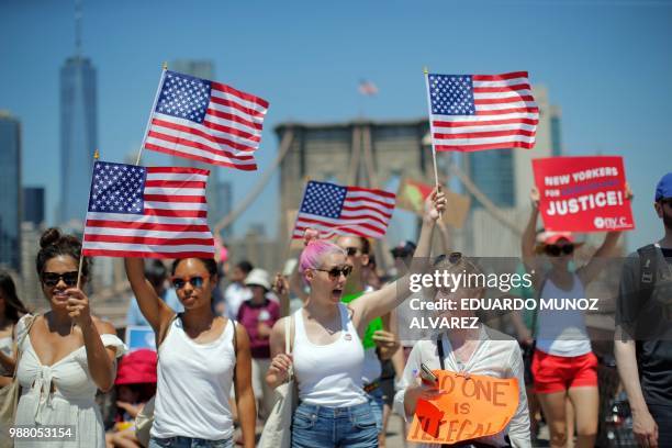 Demonstrators cross the Brooklyn Bridge during a march against the separation of immigrant families, on June 30, 2018 in New York. - Demonstrations...