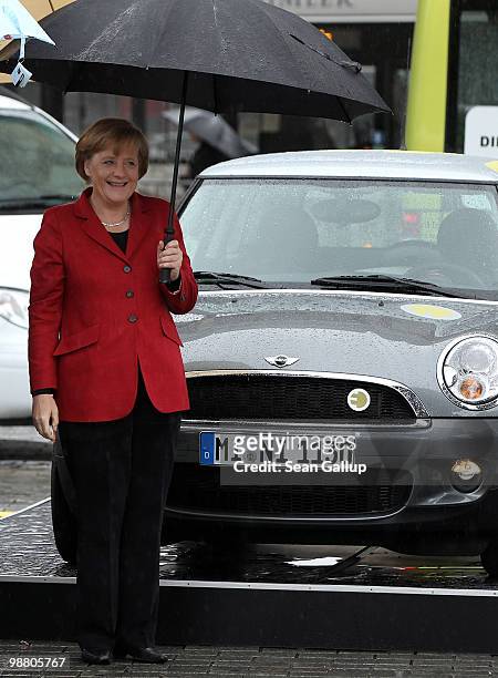 German Chancellor Angela Merkel stands next to a Mini electric car while visiting an outdoor presentation of electric cars as part of the German...