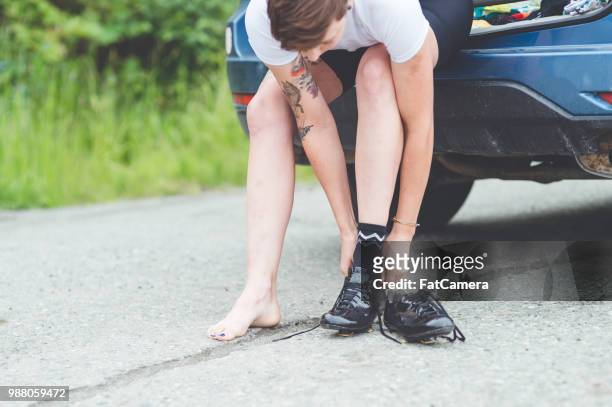 a cyclist sits on the back of a car and laces her shoes - south central alaska stock pictures, royalty-free photos & images