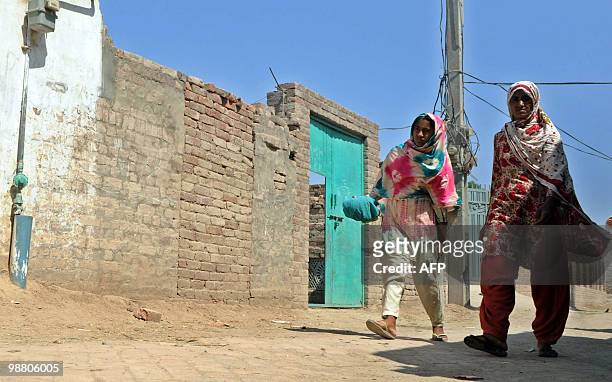 India-attacks-trial-Pakistan by Waqar Hussain Pakistani villagers walk past the assumed house of the alleged surviving gunman of the Mumbai massacre,...