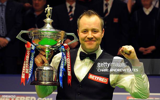Scotland's John Higgins holds the trophy after beating Britain's Shaun Murphy 18-9 to win the World Championship Snooker final at the Crucible...