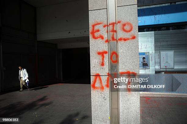 Greek man pases by a Postbank office covered with graffiti reading 'IMF out' in downtown Athens on May 3, 2010. The Greek press warned that the...