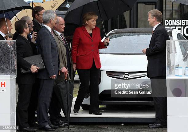 German Chancellor Angela Merkel chats with with Andreas Lassota , marketing manager for electric cars of Adam Opel AG, next to an Opel Ampera...