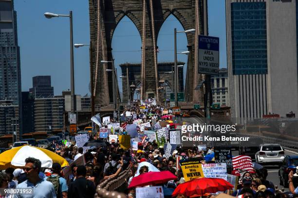 People take part during the nationwide "Families Belong Together" march as they walk by the Brooklyn Bridge on June 30, 2018 in New York City. As...