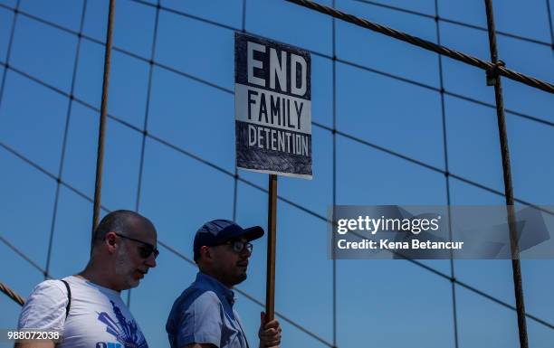 People take part during the nationwide "Families Belong Together" march as they walk by the Brooklyn Bridge on June 30, 2018 in New York City. As...