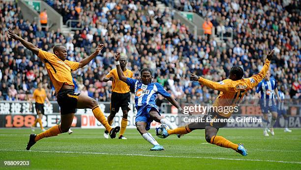 Hugo Rodallega of Wigan gets in a shot despite the efforts of Steven Mouyokolo and Bernard Mendy of Hull City during the Barclays Premier League...