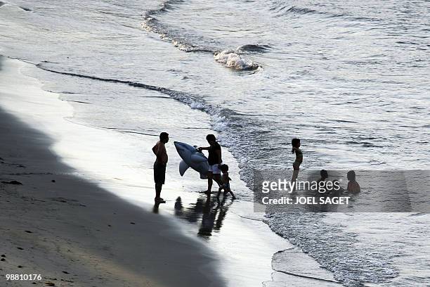 Woman wears a rubber ring representing a shark as she leads a child away from the water on April 30, 2010 on the Veracruz beach. AFP PHOTO / JOEL...
