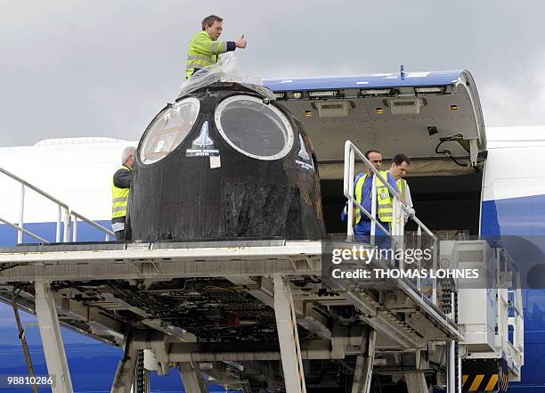 The reentry module of the Soyuz TM-19 mission is being loaded from an Airbus plane on a flat bed trailer after arriving at the airport in...
