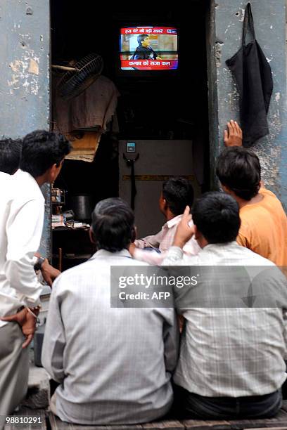 Indian people watch a television showing the Indian court verdict against alleged surviving gunman of the Mumbai massacre, Mohammed Ajmal Amir Kasab...