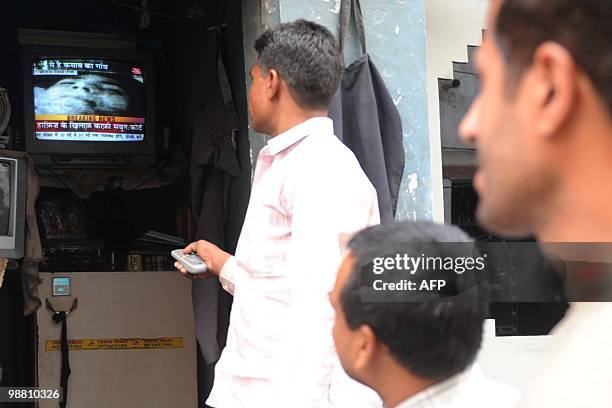 Indian people watch a television showing the Indian court verdict against alleged surviving gunman of the Mumbai massacre, Mohammed Ajmal Amir Kasab...