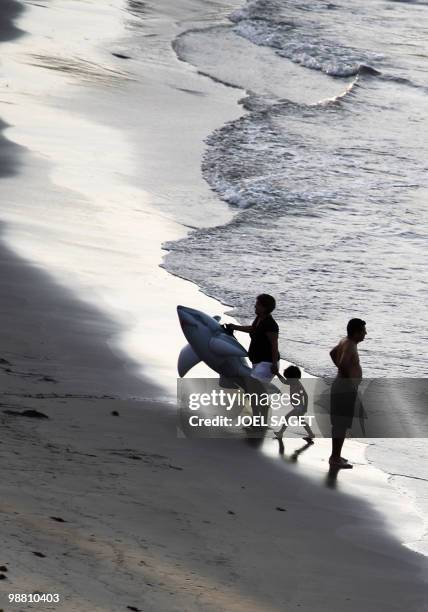 Woman wears a rubber ring representing a shark as she leads a child away from the water on April 30, 2010 on the Veracruz beach. AFP PHOTO / JOEL...