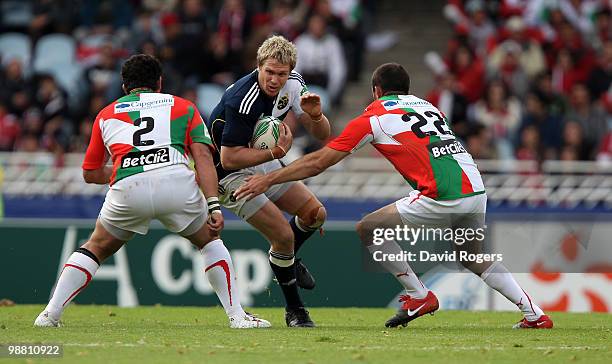 Jean de Villiers of Munster is tackled by Benoit August and Julien Peyrelongue during the Heineken Cup semi final match between Biarritz Olympique...