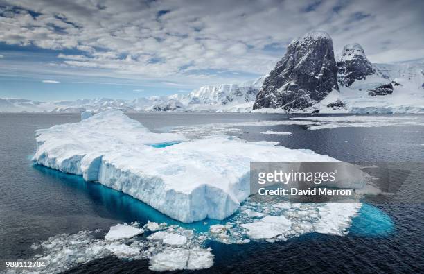 clouds over iceberg floating on water, antarctica - ghiacciai foto e immagini stock