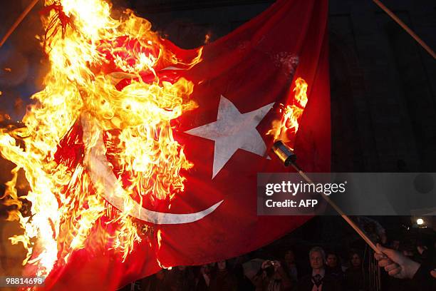 Man burns a Turkish flag while marching through the streets of Yerevan on April 23, 2010 on the eve of the 95th anniversary of Ottoman-era mass...