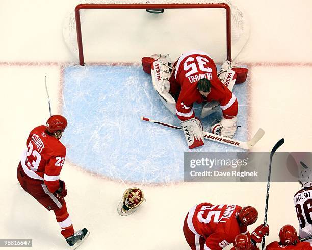 Jimmy Howard of the Detroit Red Wings has his goalie mask knocked off with a shot as teammate Niklas Kronwall and Brad Stuart defend the net during...