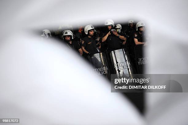 Greek riot policemen are seen through a torn banner during leftist demonstrators march in central Athens on May 3, 2010. Leading European stock...