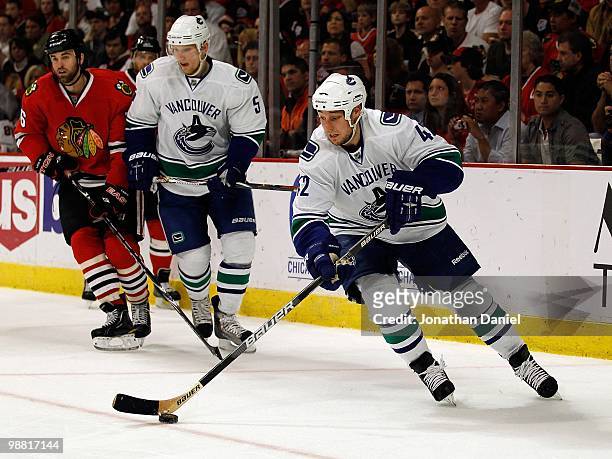 Kyle Wellwood of the Vancouver Canucks skates up the ice past teammate Christian Ehrhoff and Andrew Ladd of the Chicago Blackhawks in Game One of the...