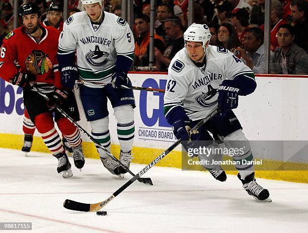 Kyle Wellwood of the Vancouver Canucks skates up the ice past teammate Christian Ehrhoff and Andrew Ladd of the Chicago Blackhawks in Game One of the...