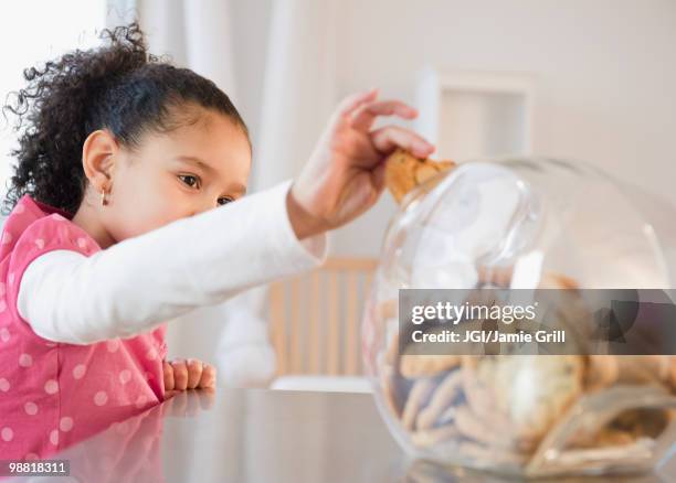 hispanic girl taking cookie from jar - child cookie jar stock-fotos und bilder