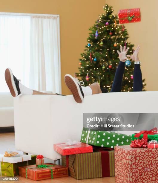 mixed race boy laying on couch with christmas gifts - gardena california stock pictures, royalty-free photos & images