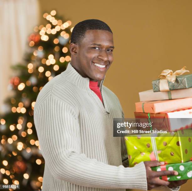 black man holding stack of christmas gifts - gardena california fotografías e imágenes de stock