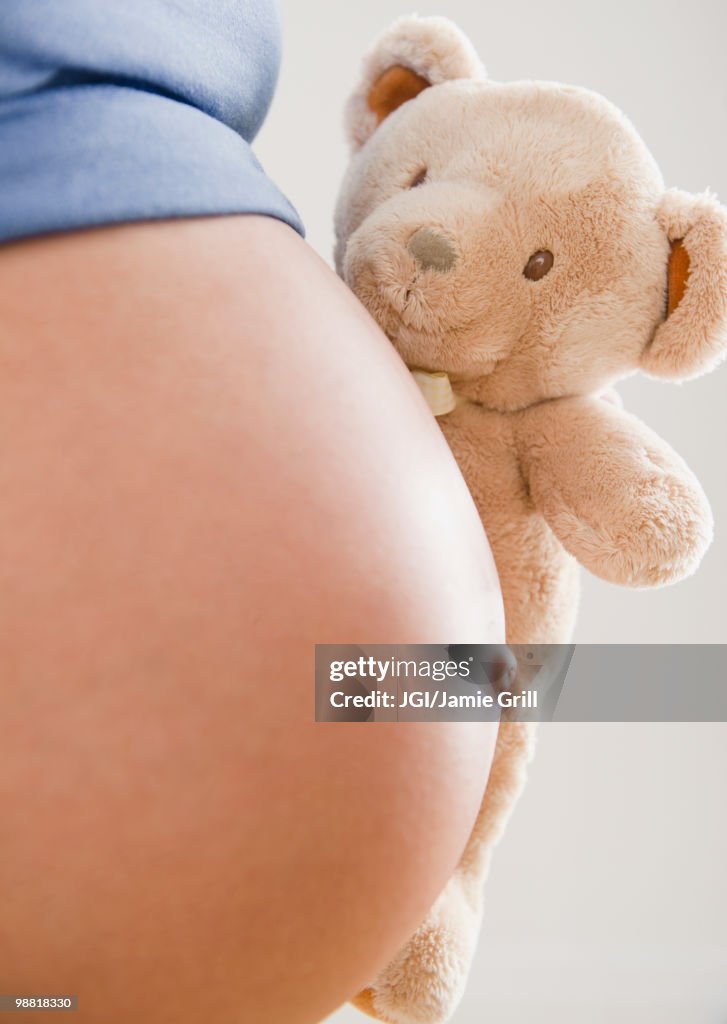 Pregnant Hispanic woman holding teddy bear