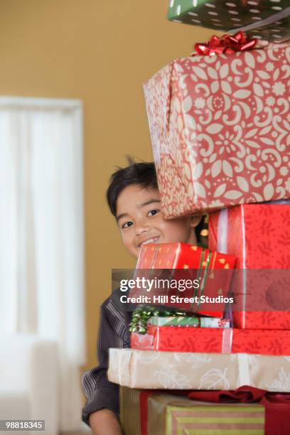 filipino boy holding stack of christmas gifts - gardena californië stockfoto's en -beelden