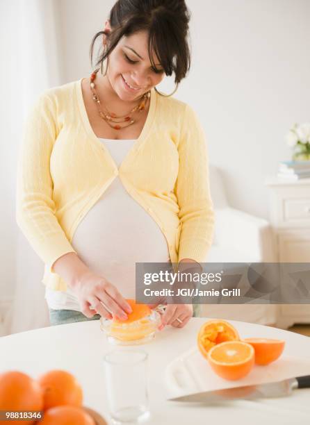 pregnant hispanic woman squeezing oranges - woman squeezing orange stockfoto's en -beelden