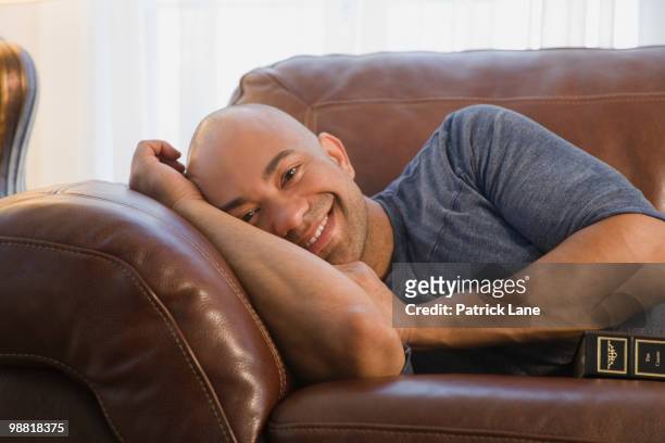 mixed race man laying on sofa - matt lane stock-fotos und bilder