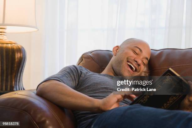 mixed race man in armchair reading book - arts express yourself 2009 stock pictures, royalty-free photos & images