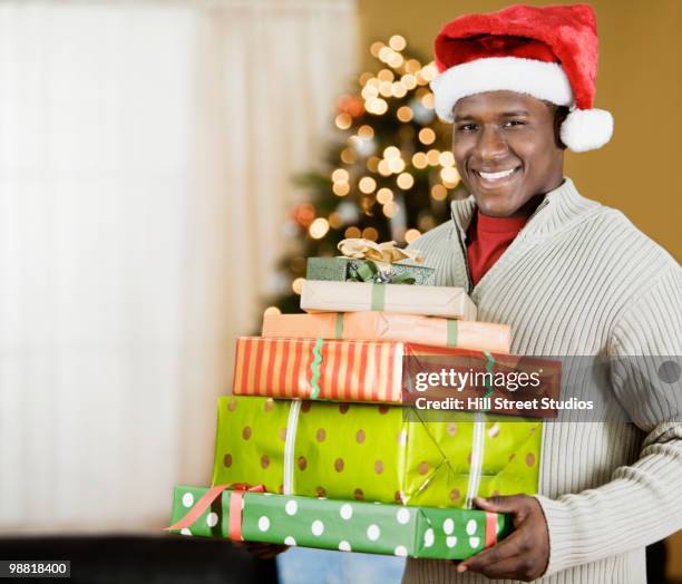 black man holding stack of christmas gifts - black christmas stockfoto's en -beelden