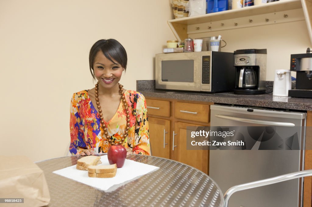 Mixed race businesswoman eating lunch in break room