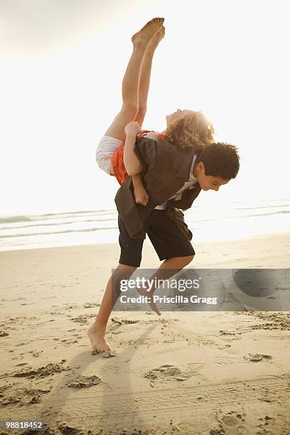 boy lifting girl on back on beach - coronado island stockfoto's en -beelden