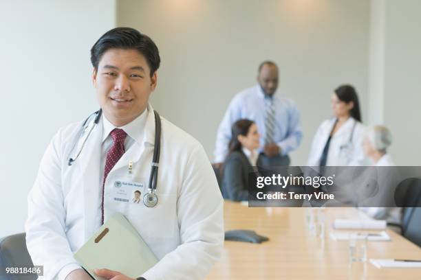 chinese doctor in conference room with co-workers - terry fair stock pictures, royalty-free photos & images