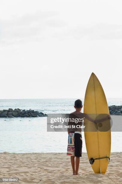 mixed race boy on beach with surfboard - inti st clair stock pictures, royalty-free photos & images