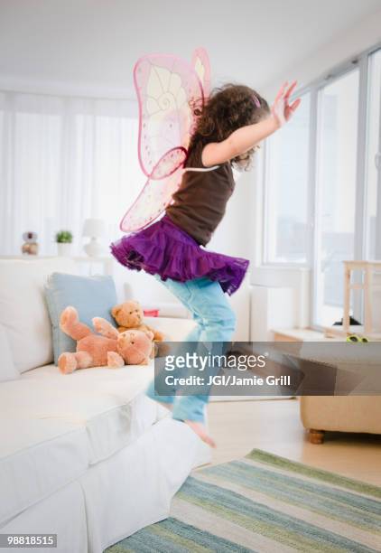 hispanic girl in fairy wings jumping off couch - djurimitation bildbanksfoton och bilder