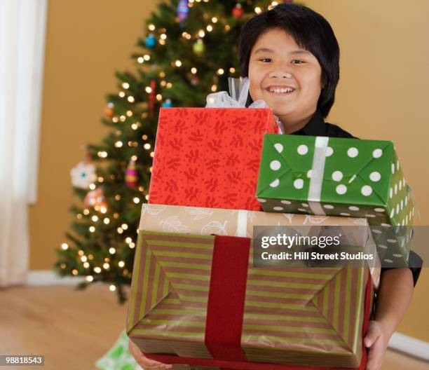 filipino boy holding stack of christmas gifts - gardena california fotografías e imágenes de stock