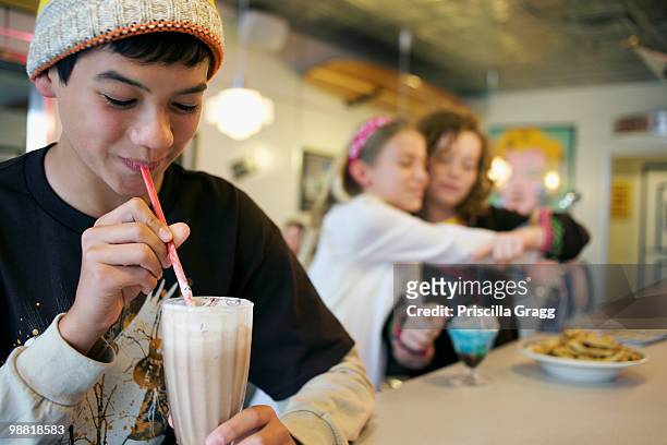 mixed race boy drinking milkshake in cafe - coronado island stockfoto's en -beelden