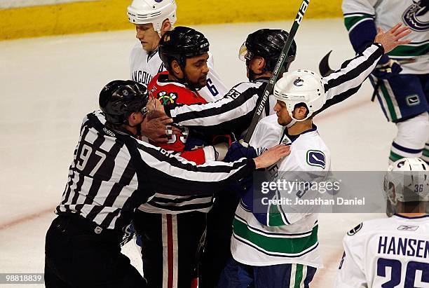 Referees break up a confrontation between Dustin Byfuglien of the Chicago Blackhawks and Kevin Bieksa of the Vancouver Canucks in Game One of the...