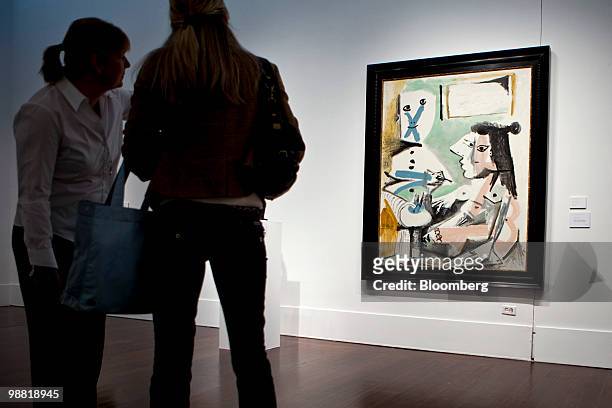 Visitors look at "Le peintre et son modele," a painting by Pablo Picasso, during a preview at Christie's International Ltd. In New York, U.S., on...