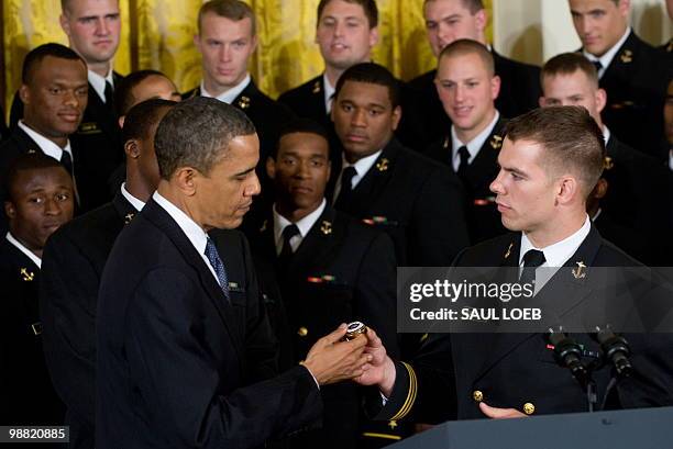 Ross Pospisil of the US Naval Academy football team gives US President Barack Obama a team ring during a ceremony where Obama presents the Commander...