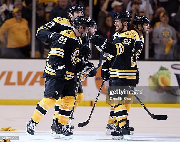 Marc Savard of the Boston Bruins is congratulated by teammates Andrew Ference and Milan Lucic after Savard scored the game winner against the...